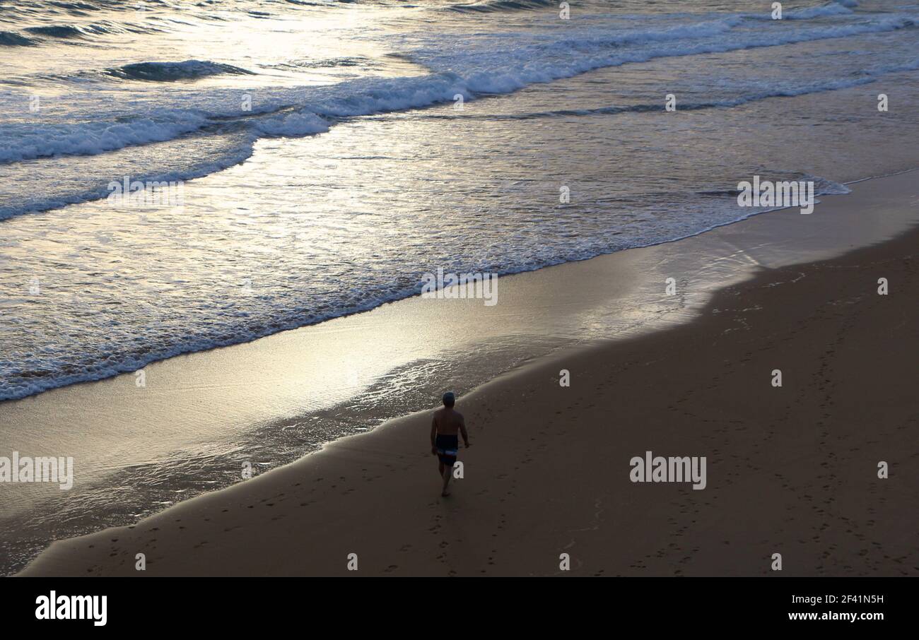 Uomo anziano che cammina in mare in tronchi da nuoto in una fredda mattina invernale per una nuotata Santander Cantabria Spagna Foto Stock