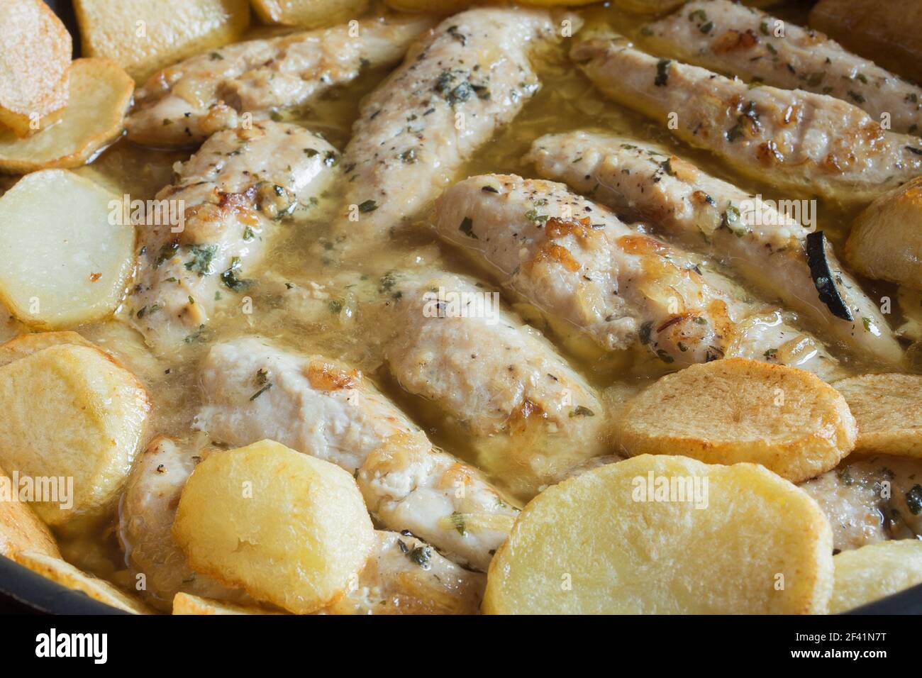 Ricetta di filetti di pollo con aglio e spezie in salsa verde accompagnata da patate al forno. Cibo fatto in casa. Foto Stock