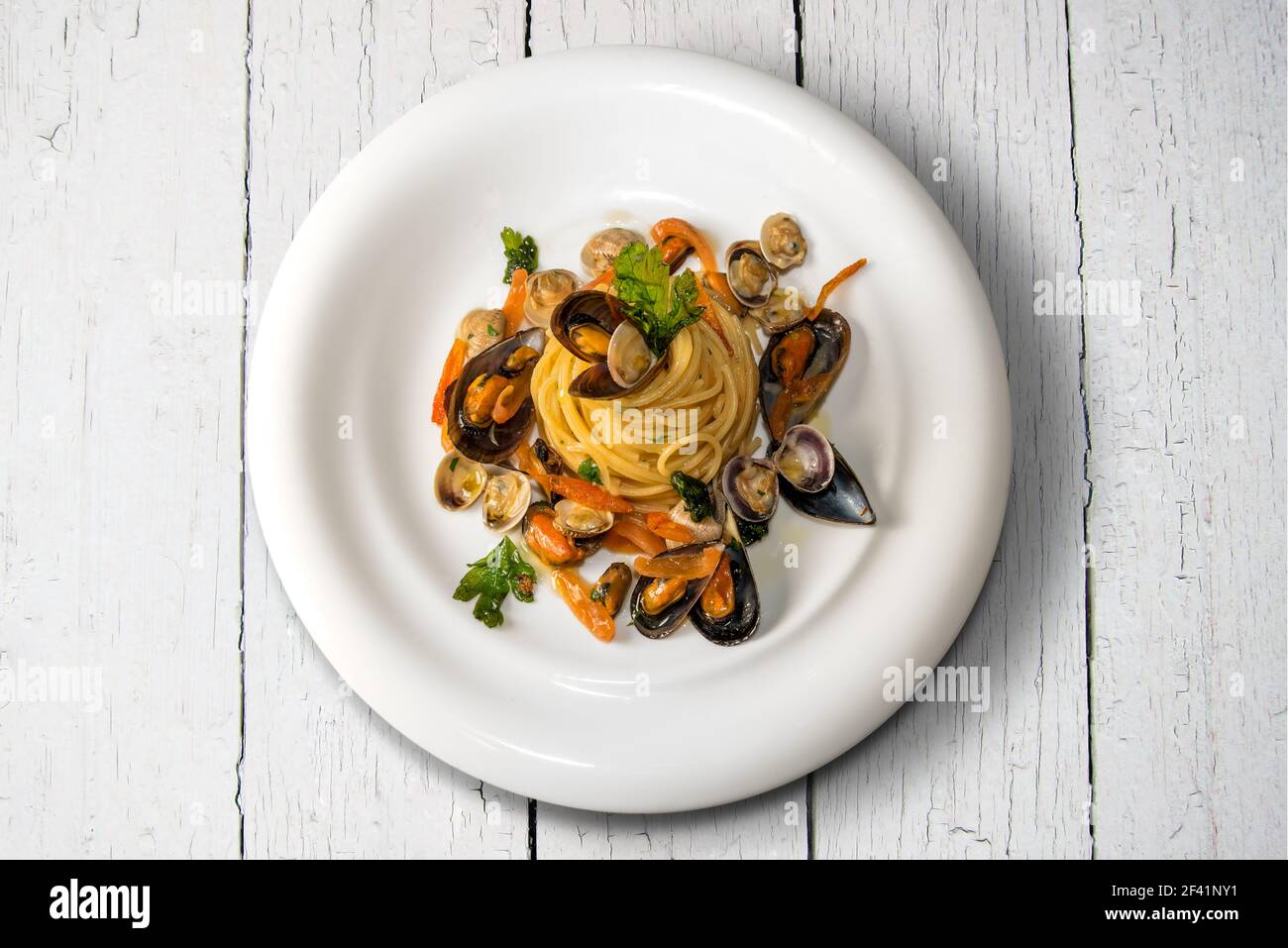 pasta di pesce, spaghetti italiani con vongole cozze e prezzemolo nel piatto bianco su tavole di legno di colore bianco, vista dall'alto piatto Foto Stock