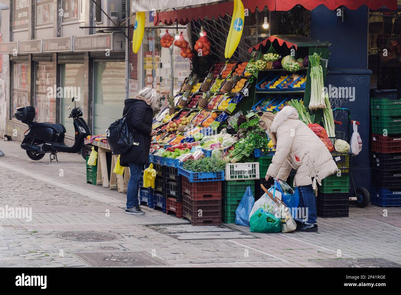 Salonicco, Grecia - Marzo 13 2021: Persone fuori negozio di greengrocer con mascherine covid-19. Negozio di alimentari con folla non identificata che indossa maschere protettive all'ingresso del negozio nel centro della città. Foto Stock