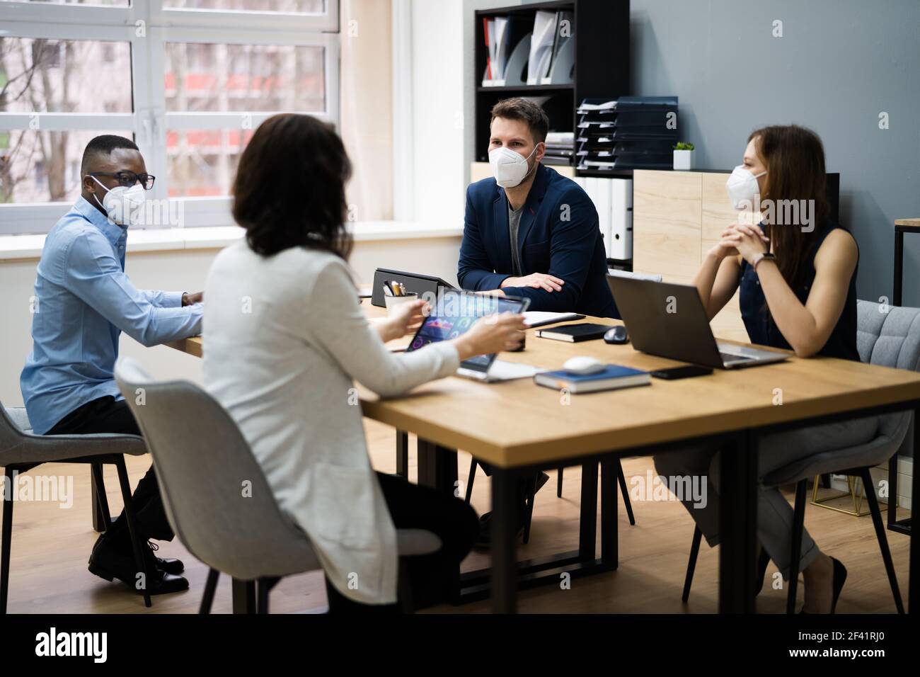 Gruppo di persone aziendali si incontrano in maschere facciali Foto Stock