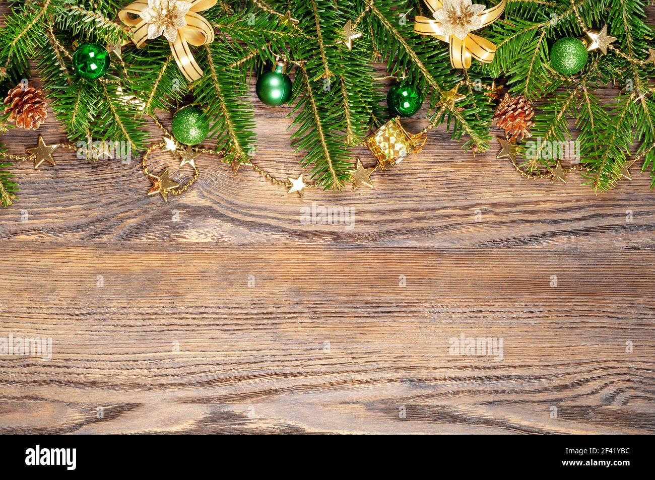 Decorazioni natalizie dorate e verdi e ramificazioni di abete su un sfondo di legno Foto Stock