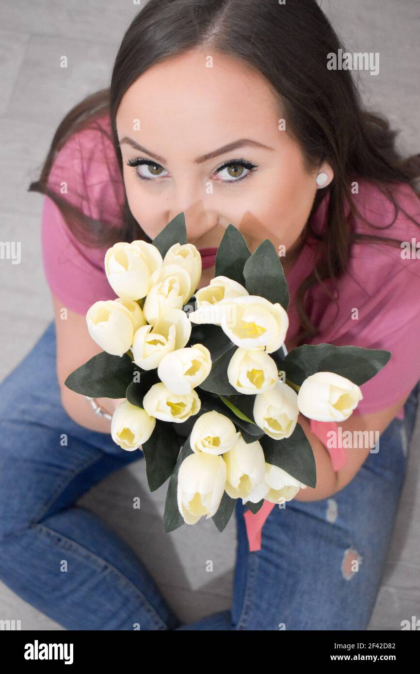 Bella donna all'interno che tiene tulipani bianchi Foto Stock
