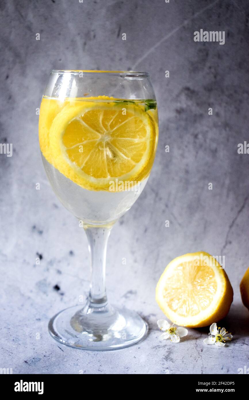 Limoni e un bicchiere di limonata su sfondo grigio Foto Stock