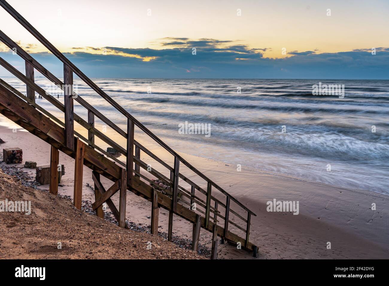 una scalinata in legno che permette di raggiungere la spiaggia molto vicina al litorale dell'acqua, proprio come entrare direttamente nell'acqua di mare Foto Stock