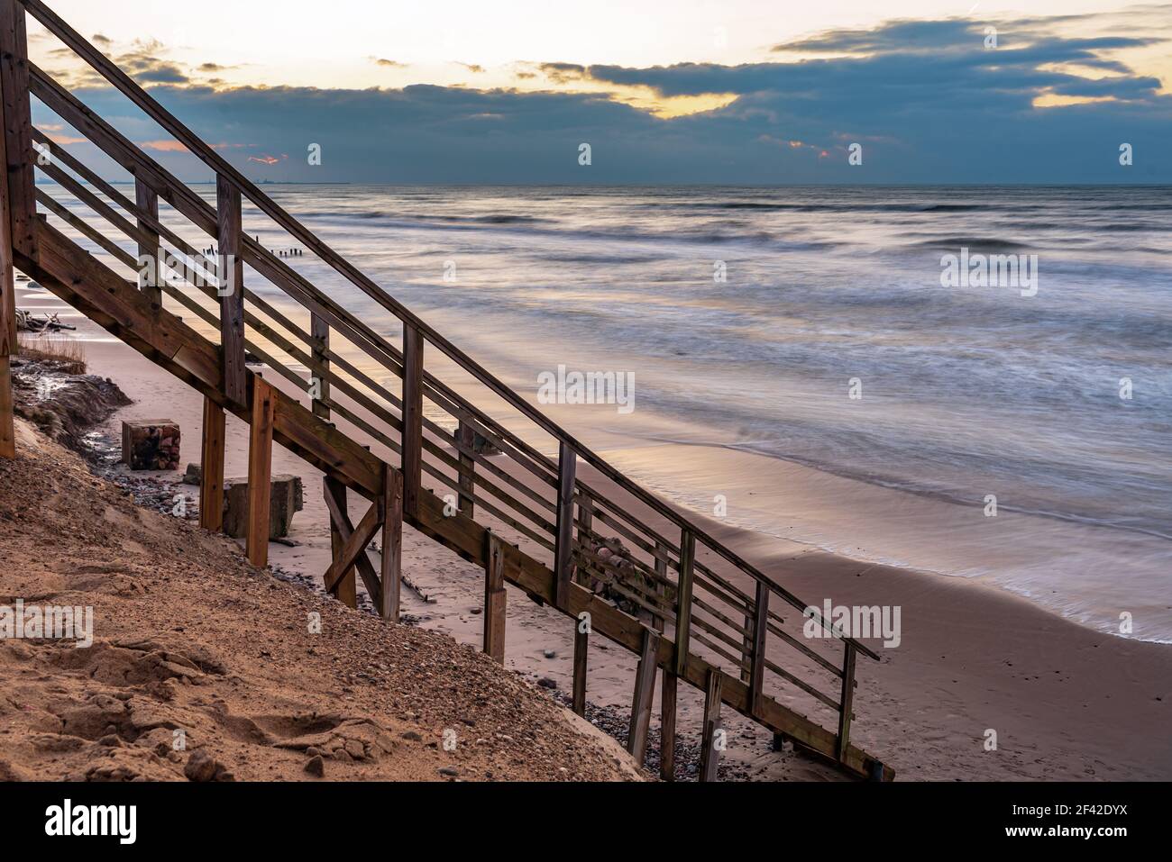 una scalinata in legno che permette di raggiungere la spiaggia molto vicina al litorale dell'acqua, proprio come entrare direttamente nell'acqua di mare Foto Stock