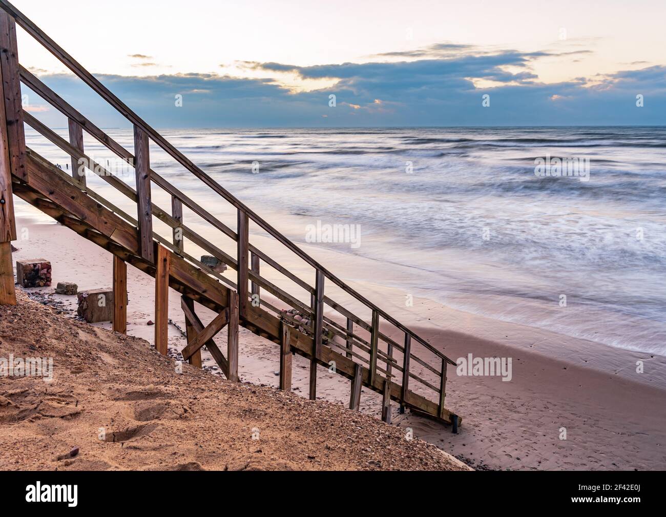 una scalinata in legno che permette di raggiungere la spiaggia molto vicina al litorale dell'acqua, proprio come entrare direttamente nell'acqua di mare Foto Stock