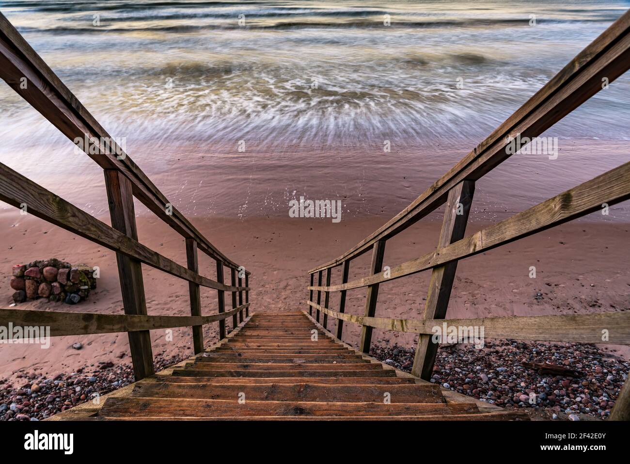 una scalinata in legno che permette di raggiungere la spiaggia molto vicina al litorale dell'acqua, proprio come entrare direttamente nell'acqua di mare Foto Stock