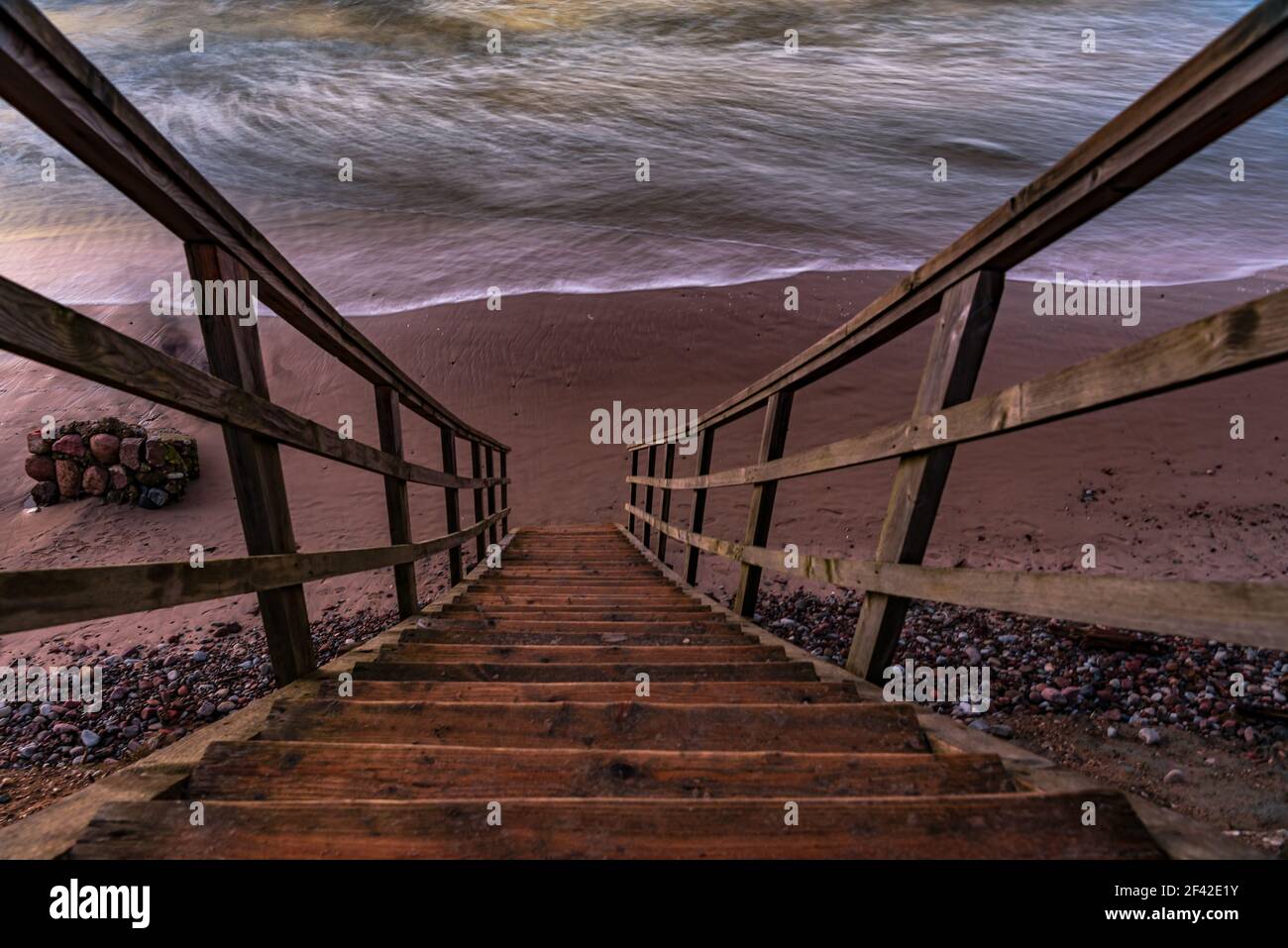 una scalinata in legno che permette di raggiungere la spiaggia molto vicina al litorale dell'acqua, proprio come entrare direttamente nell'acqua di mare Foto Stock