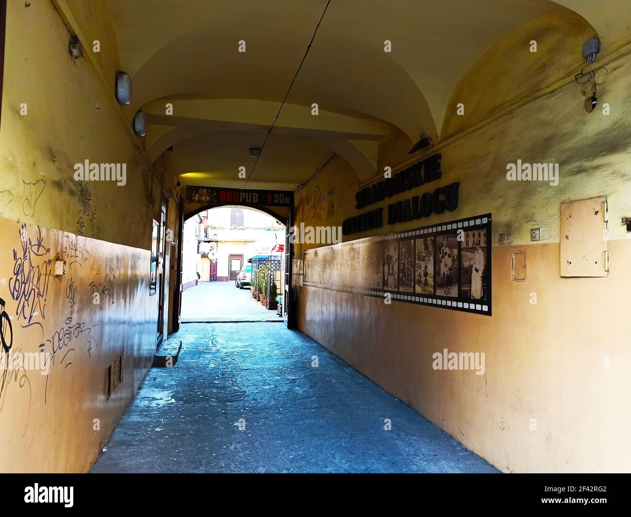 Cracovia, Polonia - 12 ottobre 2019: Passaggio medievale ad arco alla piazza commerciale della città vecchia di cracovia con fotografie appese alle mura Foto Stock