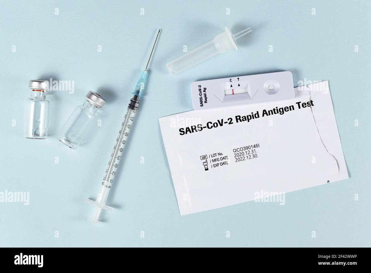 Strumenti per combattere la pandemia del virus Corona, incluso il test rapido dell'antigene e flaconcini di vaccino con siringa Foto Stock