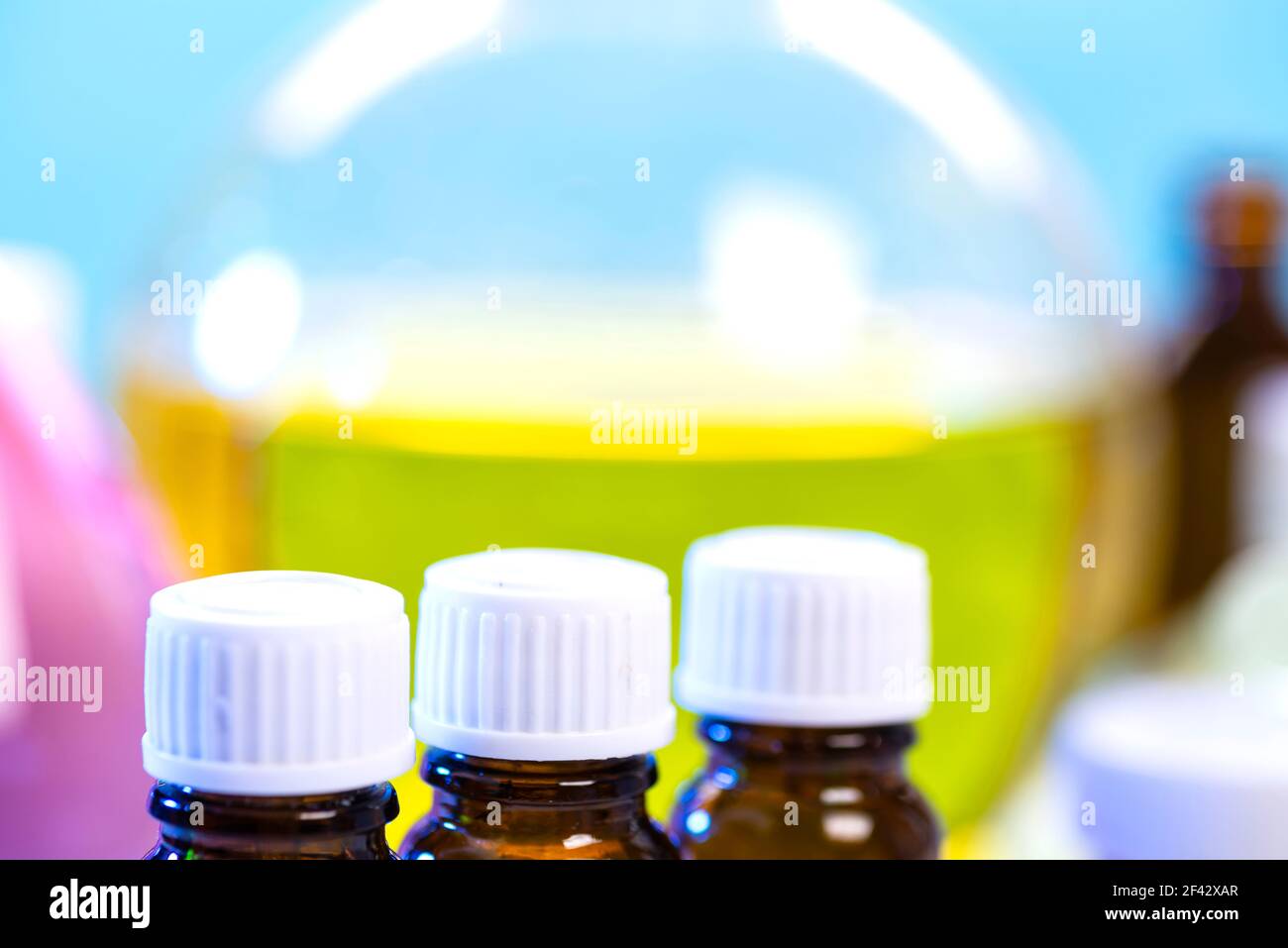 Un set di matracci con reagenti chimici sullo sfondo di un matraccio di vetro grande con una soluzione gialla in un vero laboratorio. Laboratorio chimico con Foto Stock