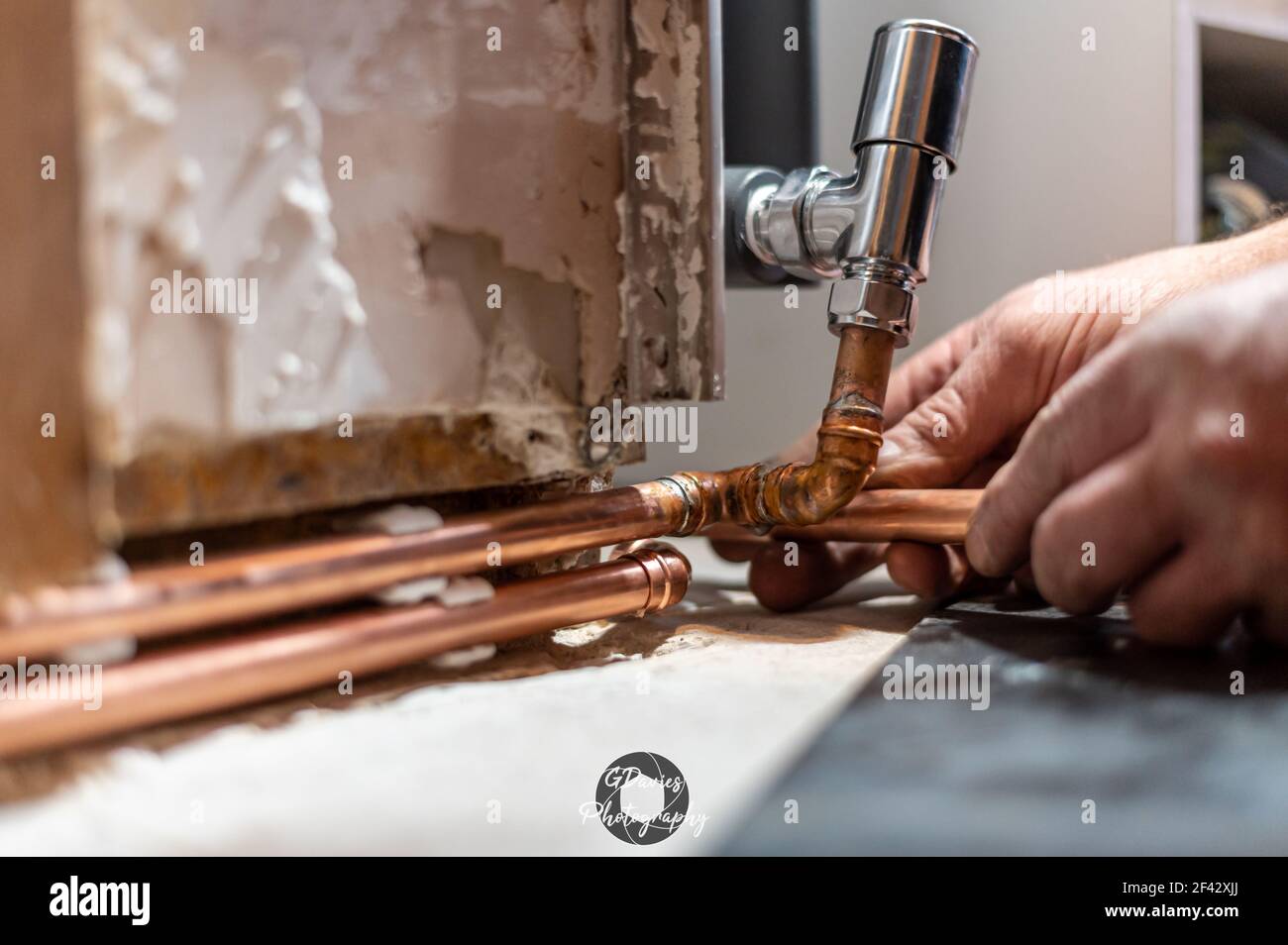 Primo piano di mani maschili che tubano il nuovo radiatore a casa pronto per essere saldato. Concetto diy Foto Stock