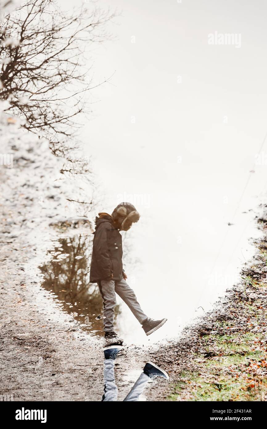 Riflessione di ragazzo e cielo sovrastato in puddle Foto Stock