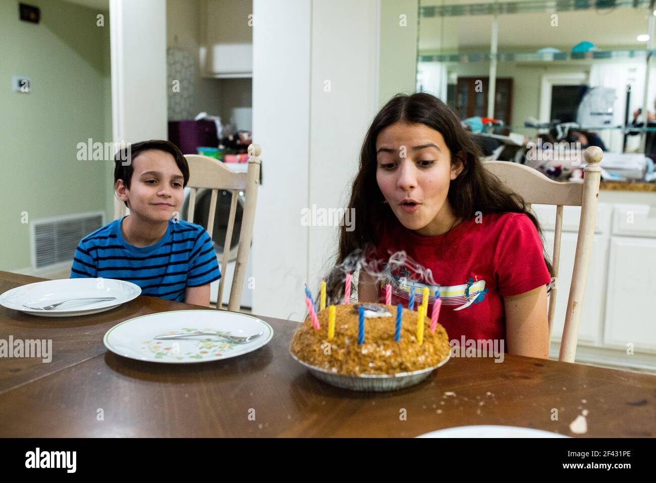 La ragazza teen soffia fuori le candele sulla torta di compleanno Foto Stock