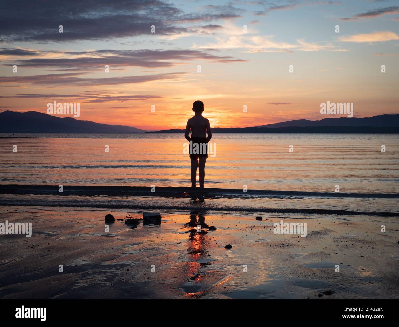 Ragazzo che pagaiava nella baia di Ganavan, Oban la sera Foto Stock