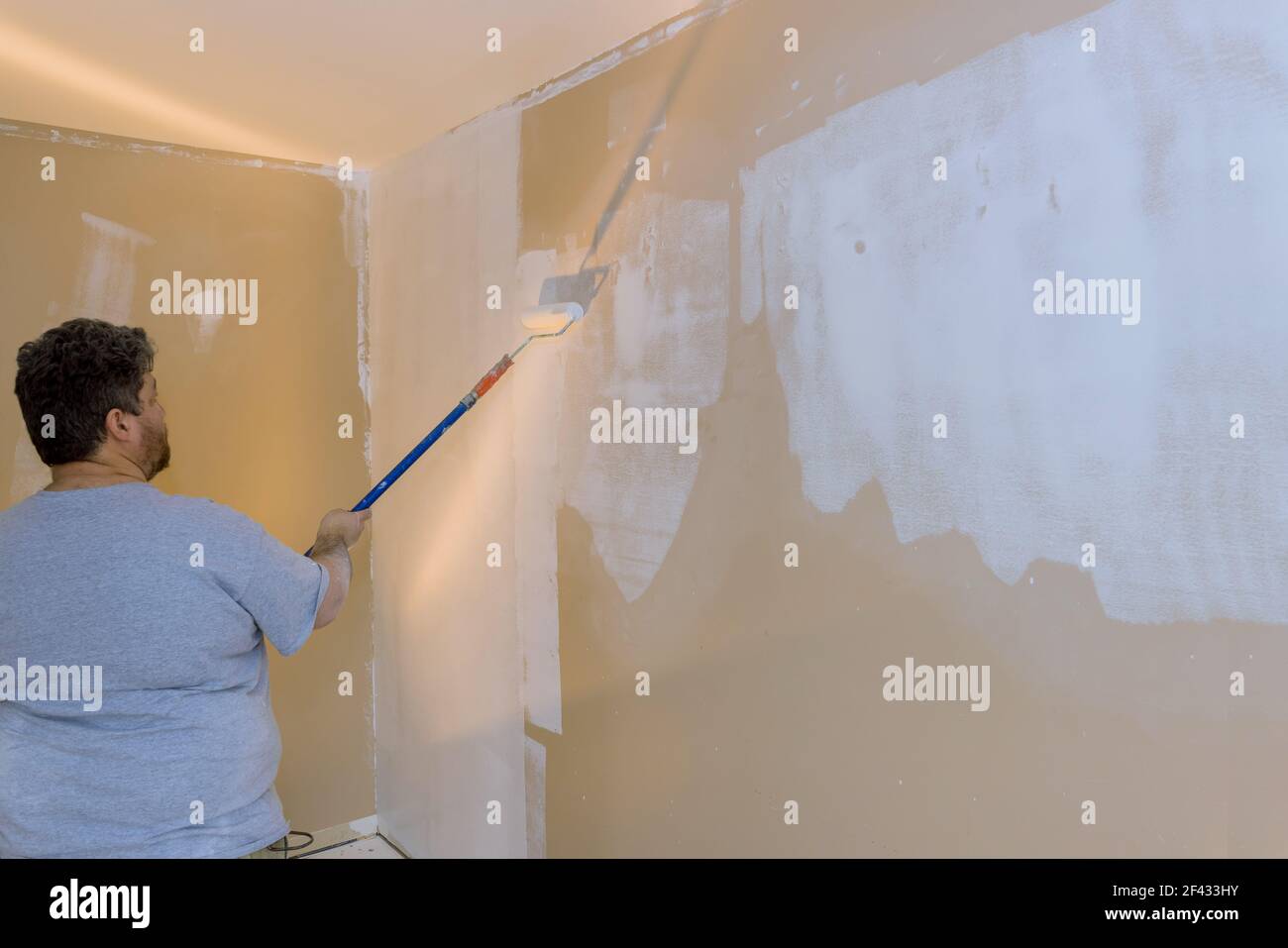 Eseguire l'adescamento con un rullo di vernice e riparare la parete dopo l'applicazione di intonaco per lavori interni Foto Stock