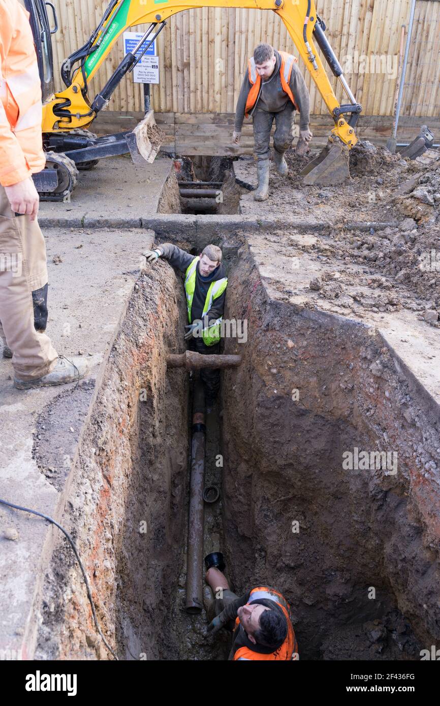 Costruttori in alta viz scavare la strada, buco profondo per installare tubo fognario sotterraneo per la casa residenziale, Londra Foto Stock