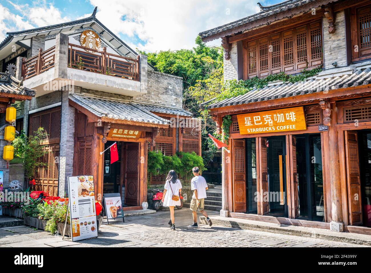 Dali China, 5 ottobre 2020: Caffetteria Starbucks con nome e logo in una vecchia casa cinese in legno e la gente asiatica che entra nel centro storico di Dali Y Foto Stock