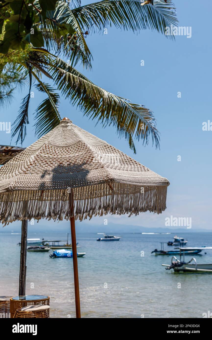 Ombrellone coccinato sulla spiaggia di Sanur. Oceano, barche, cielo blu. Bali, Indonesia. Immagine verticale. Foto Stock