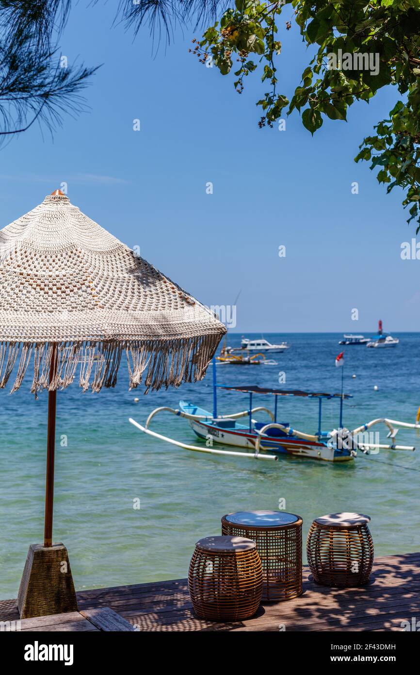 Ombrellone coccinato sulla spiaggia di Sanur. Oceano, barche, cielo blu. Bali, Indonesia. Immagine verticale. Foto Stock