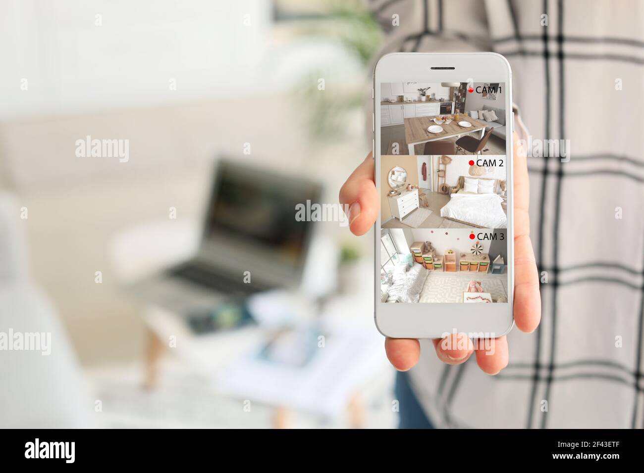 Donna che mostra telefono cellulare con immagini di telecamere cctv installate in appartamento su schermo, primo piano Foto Stock
