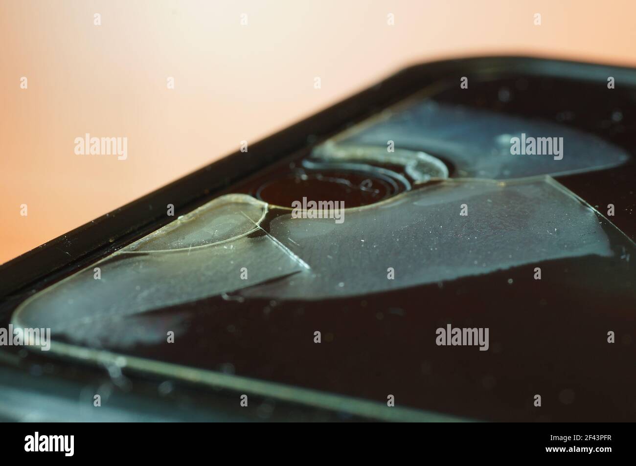 Vetro protettivo dello smartphone - danneggiato, incrinato, usurato. Vecchia protezione dello schermo. Telefono sporco, nero, logoro. Foto Stock