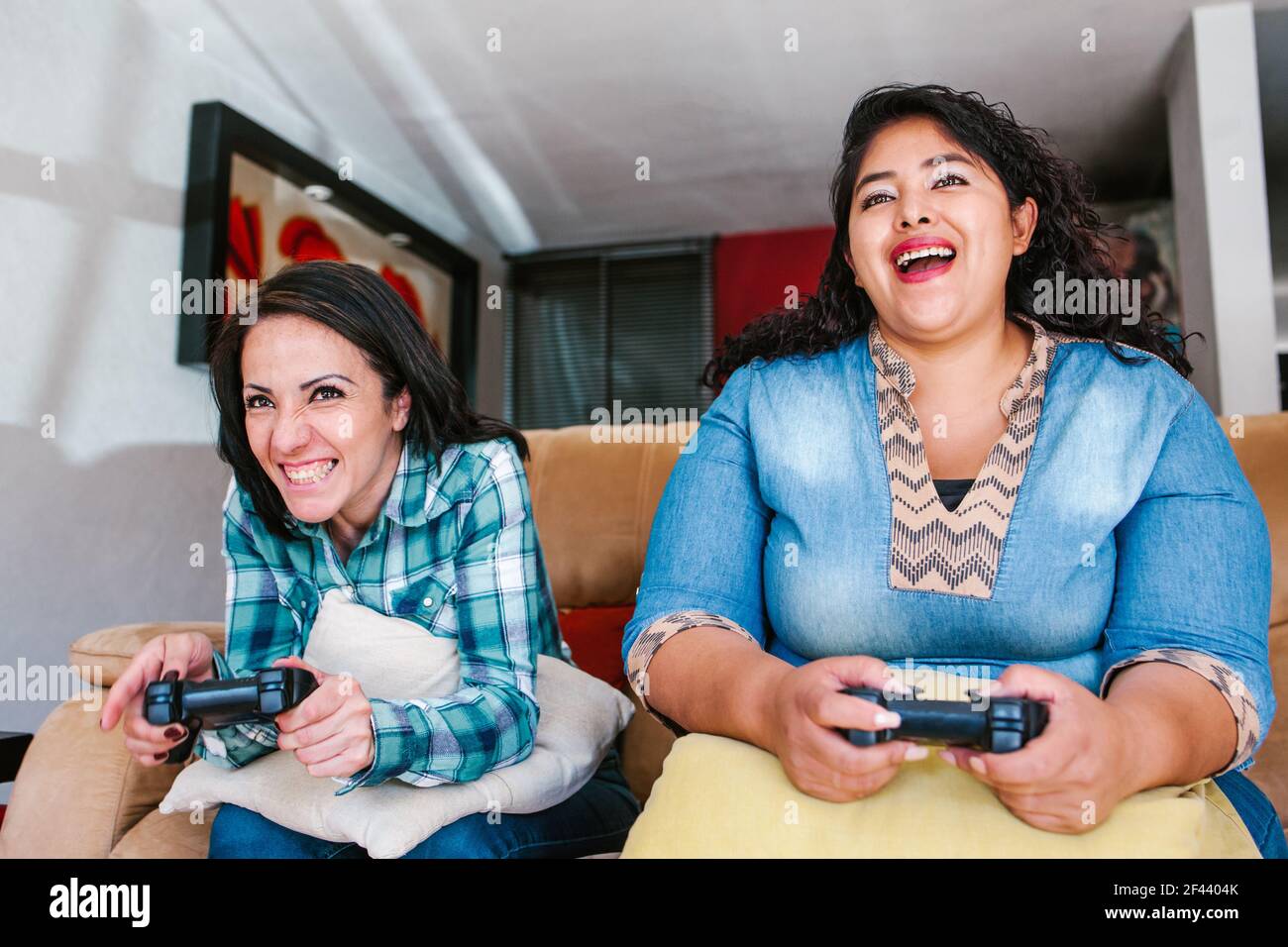 Due migliori amici latini che si siedono a casa giocando a giochi Su console in Messico Foto Stock