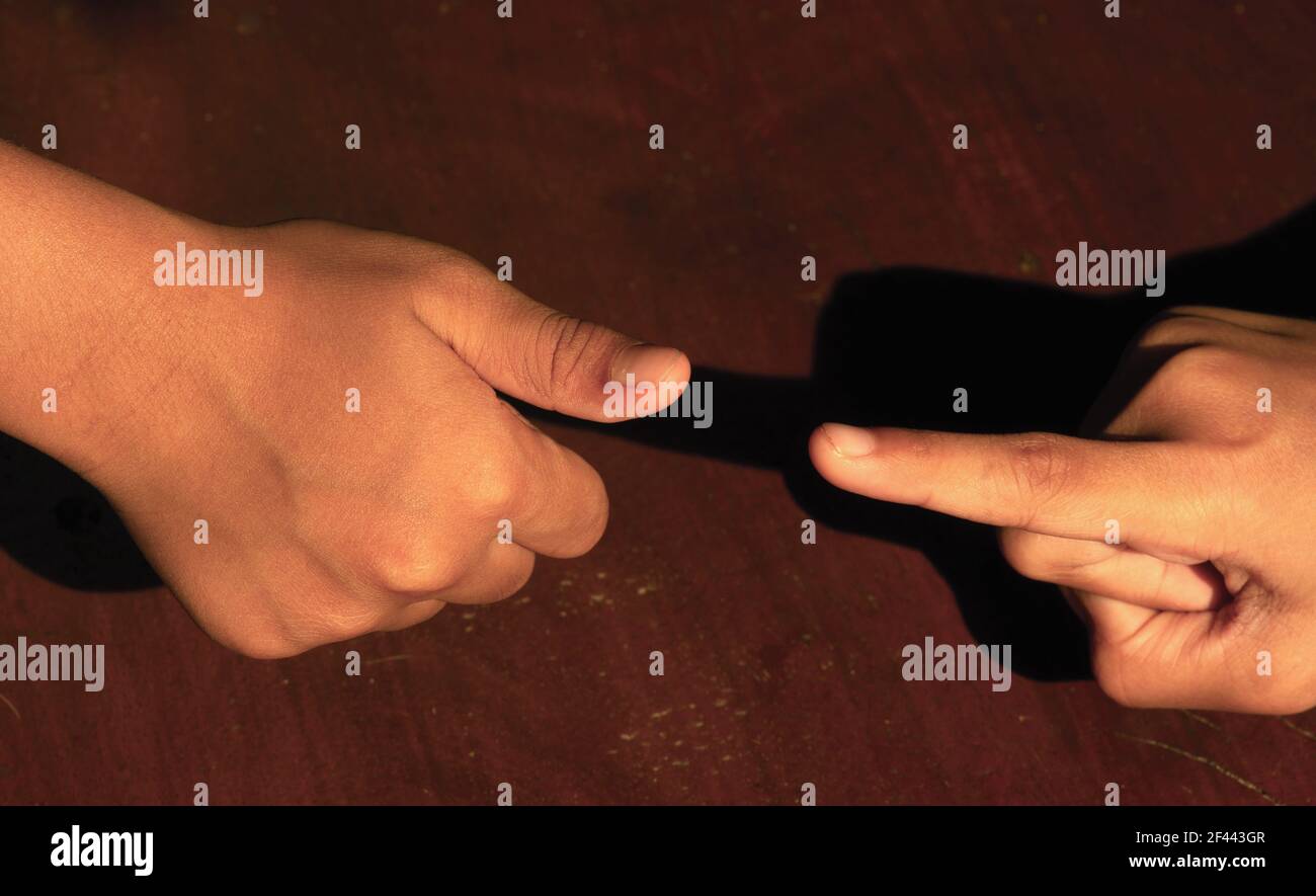 Forbici di carta di pietra di gioco sul tavolo di legno, con un dito e un pollice. Concetto di concorrenza aziendale. Foto Stock
