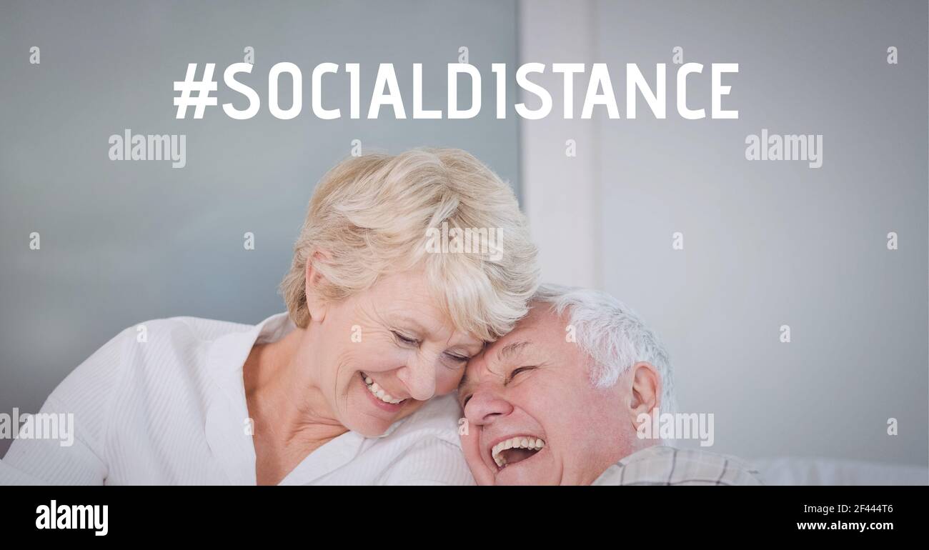 Testo distanza sociale sopra sorridente coppia anziana a casa Foto Stock