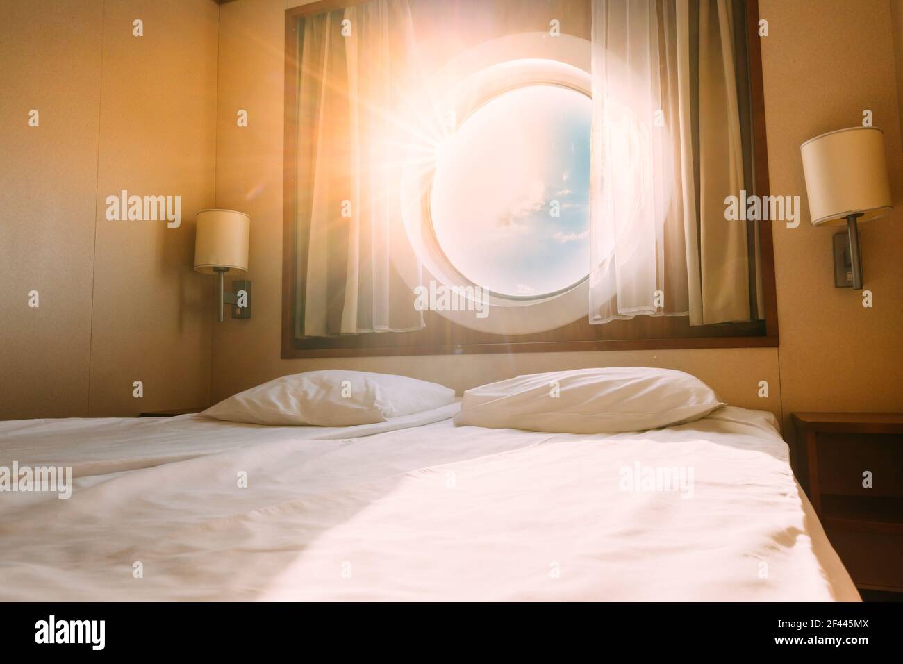 Luce solare naturale che brilla attraverso la finestra della nave in cabina artigianale con letto. Vista sul mare. Cabina di lusso su traghetto o nave da crociera. Vacanza crociera sul mare Foto Stock