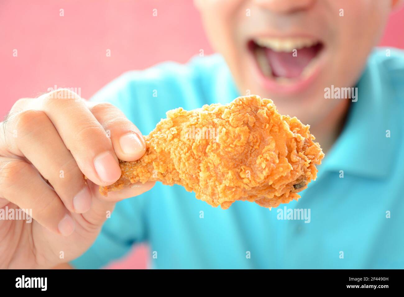 Un uomo con bocca aperta circa a mangiare fritto profondo coscia di pollo o bastone di pollo Foto Stock