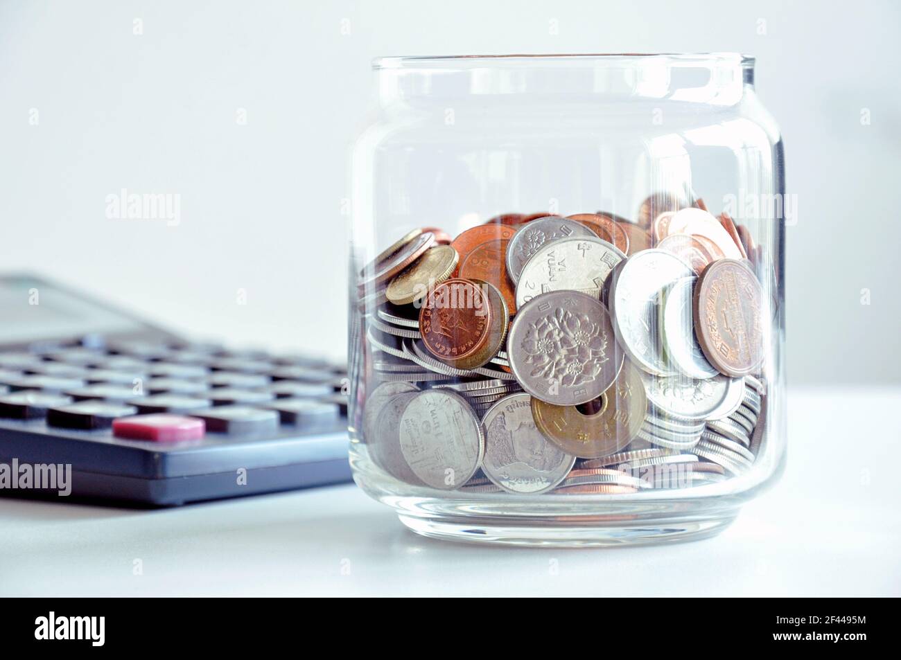 Monete nel vaso di vetro (valute asiatiche miste) - concetto di risparmio Foto Stock