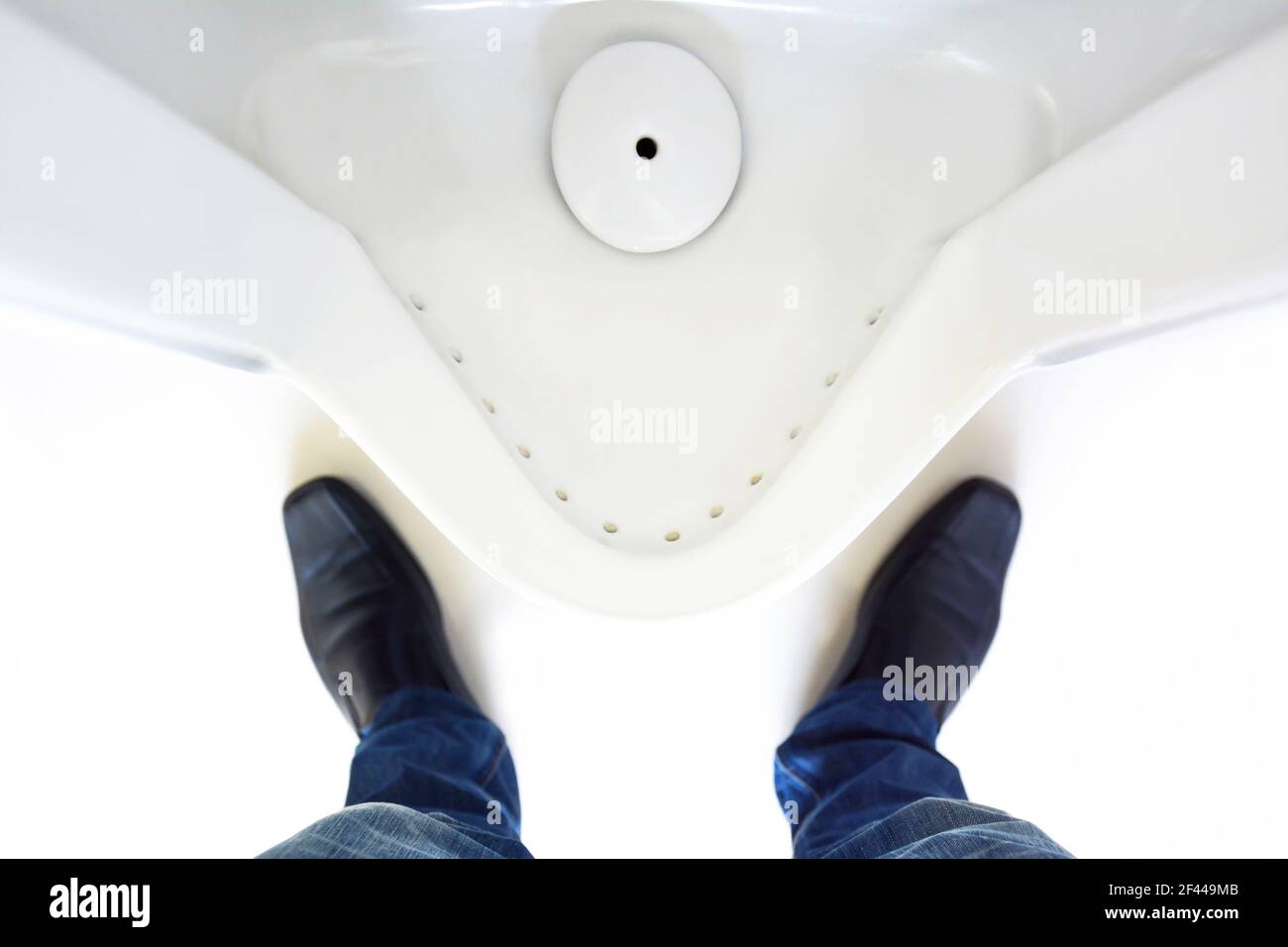 Vista dall'alto delle gambe di un uomo davanti all'orinatoio in uomini wc Foto Stock