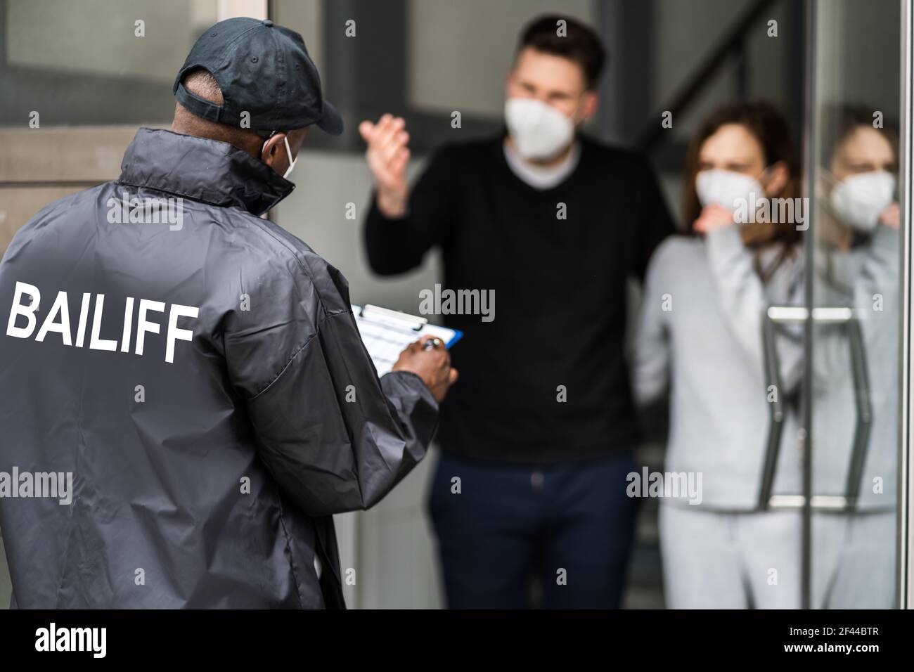 Bailiff debt Collector a Door in Mask Foto Stock