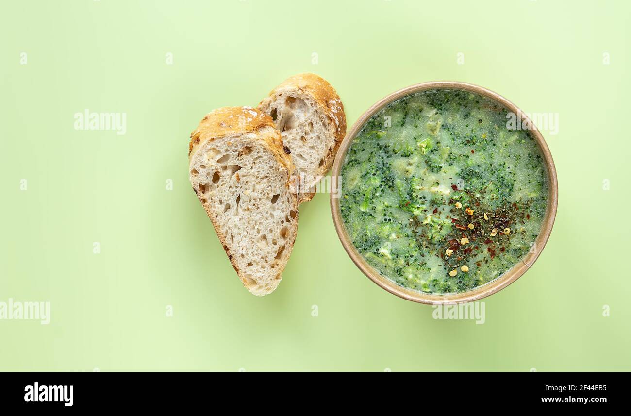 Concetto di alimentazione sana. Zuppa di crema di broccoli fresca servita pane fresco e spezie in contenitore artigianale. Foto Stock