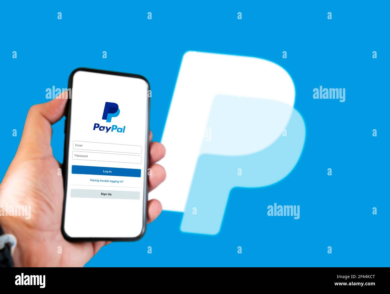 Roma, Italia, 16 febbraio 2021: Mano che tiene uno smartphone con la pagina  di login dell'app Paypal sullo schermo e logo Paypal sfocato sullo sfondo.  Trasferimento di denaro Foto stock - Alamy