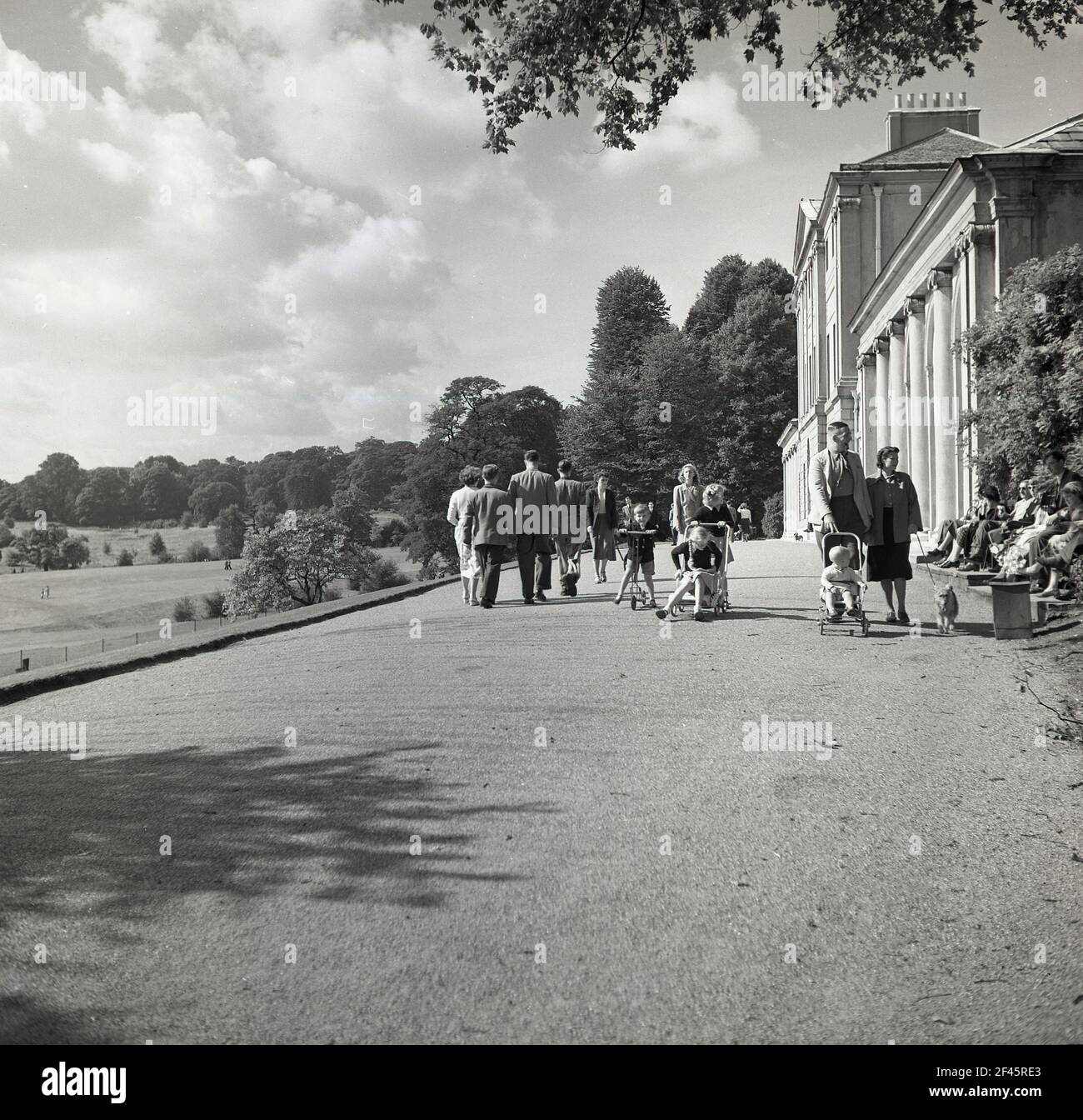 1950s, storico, familes fuori Kenwood House a Hampstead Heath, North London, Inghilterra, Regno Unito. Una casa signorile, originariamente costruita nel 17th ° secolo, è stato ristrutturato da Robert Adam tra il 1764 e il 1779 e fu la casa dei conti di Mansfield. Nel 1925 la casa e parte del parco fu acquistata da Edward Guinness, 1st conte di Iveagh, che donò la proprietà alla nazione. Il London County Council ne prese possesso e, alla fine degli anni '1920s, fu aperto al pubblico. Foto Stock