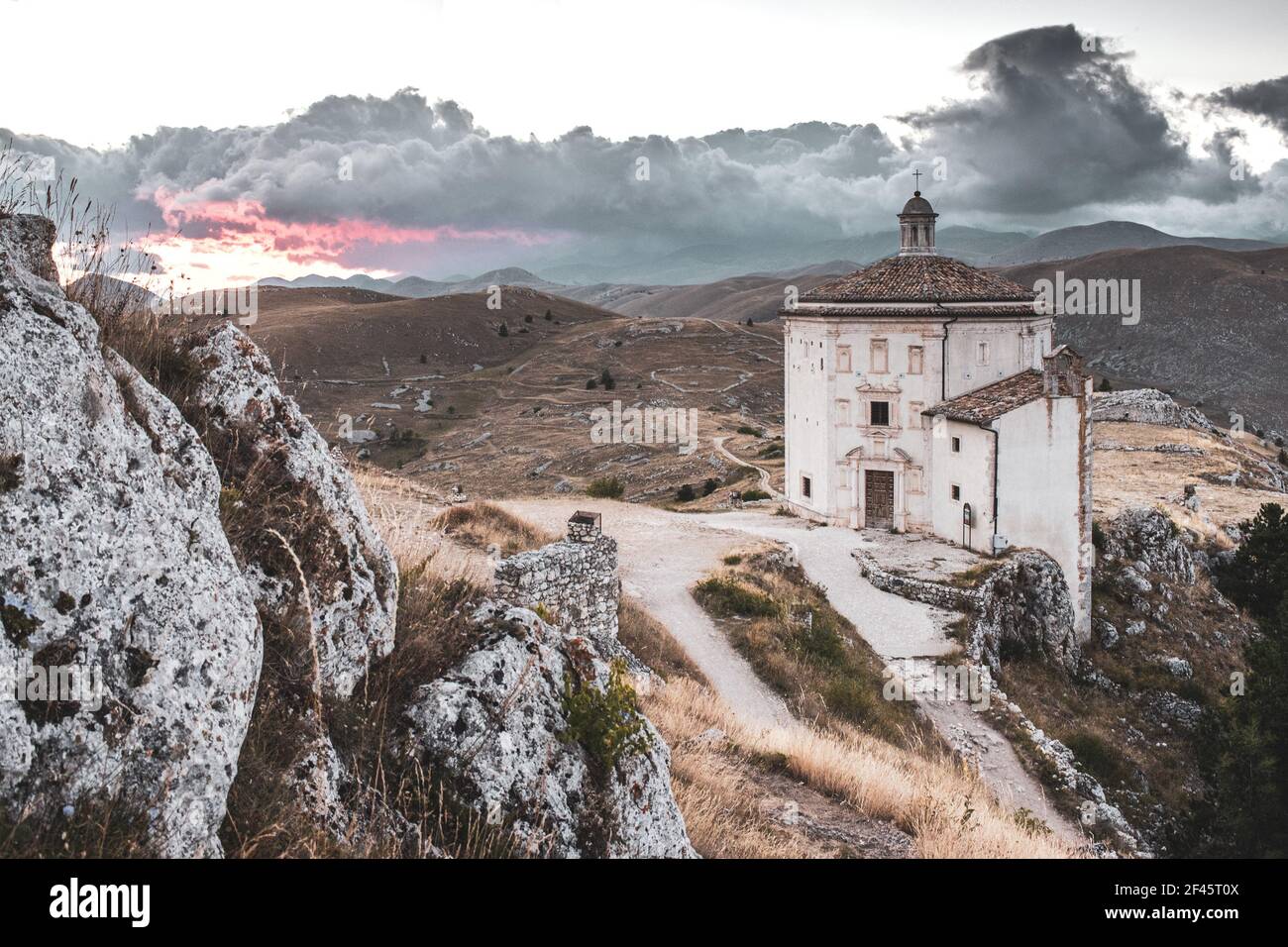 ITALIA, CALASCIO: Vista al tramonto sulla chiesa di Santa Maria della Pietà, situata nei pressi del castello medievale normanno di Calascio. Sullo sfondo, nascosto dietro le nuvole, il Monte Corno Grande. Foto Stock