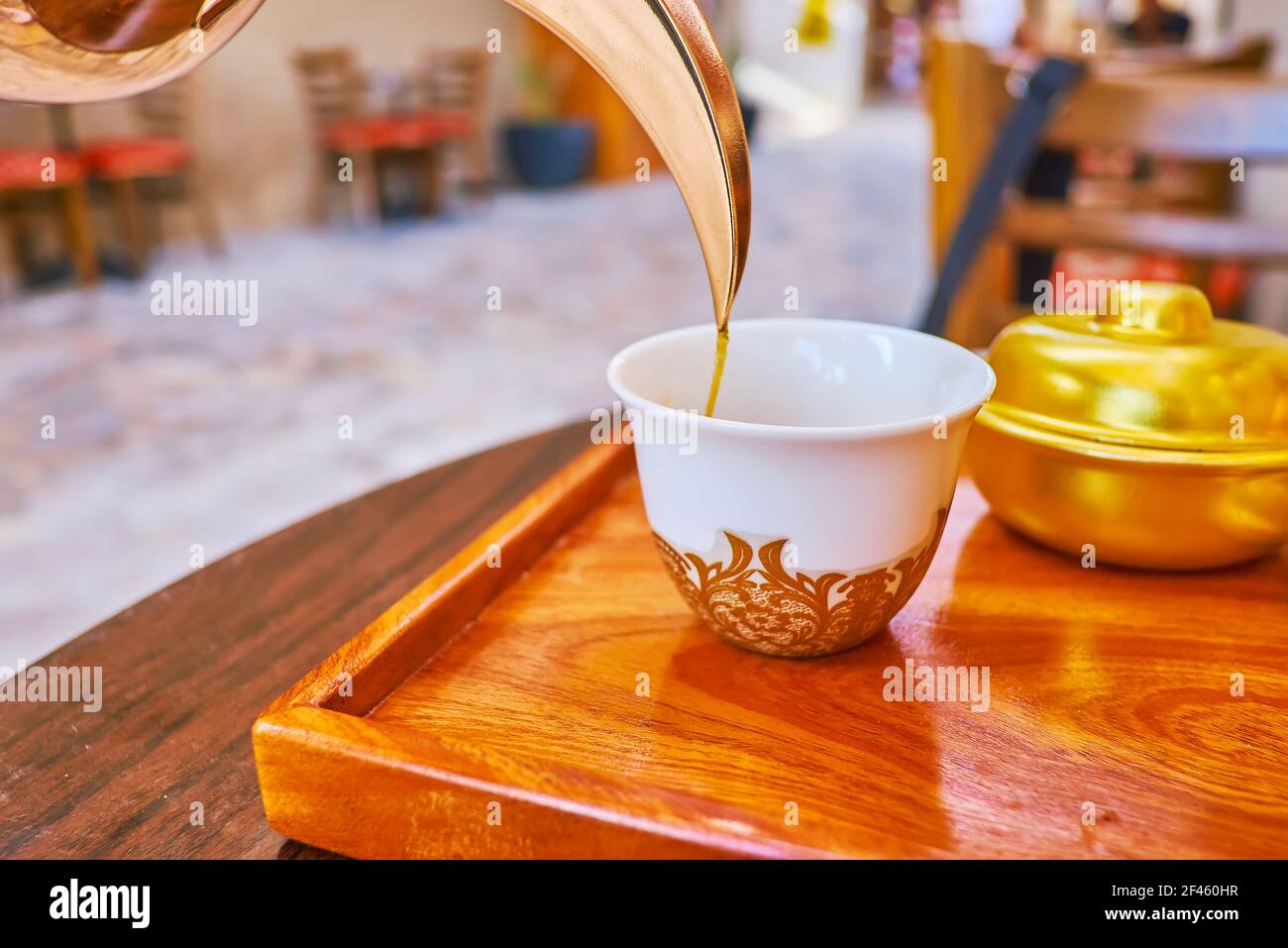 Primo piano del caffè che si versa dalla caffettiera Dallah alla tradizionale ciotola da caffè, Dubai, Emirati Arabi Uniti Foto Stock