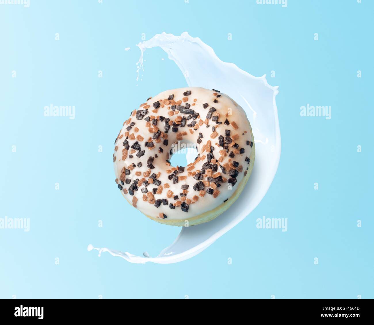Ciambella fresca con spruzzi di latte su sfondo blu. Concetto di cibo minimo. Foto Stock