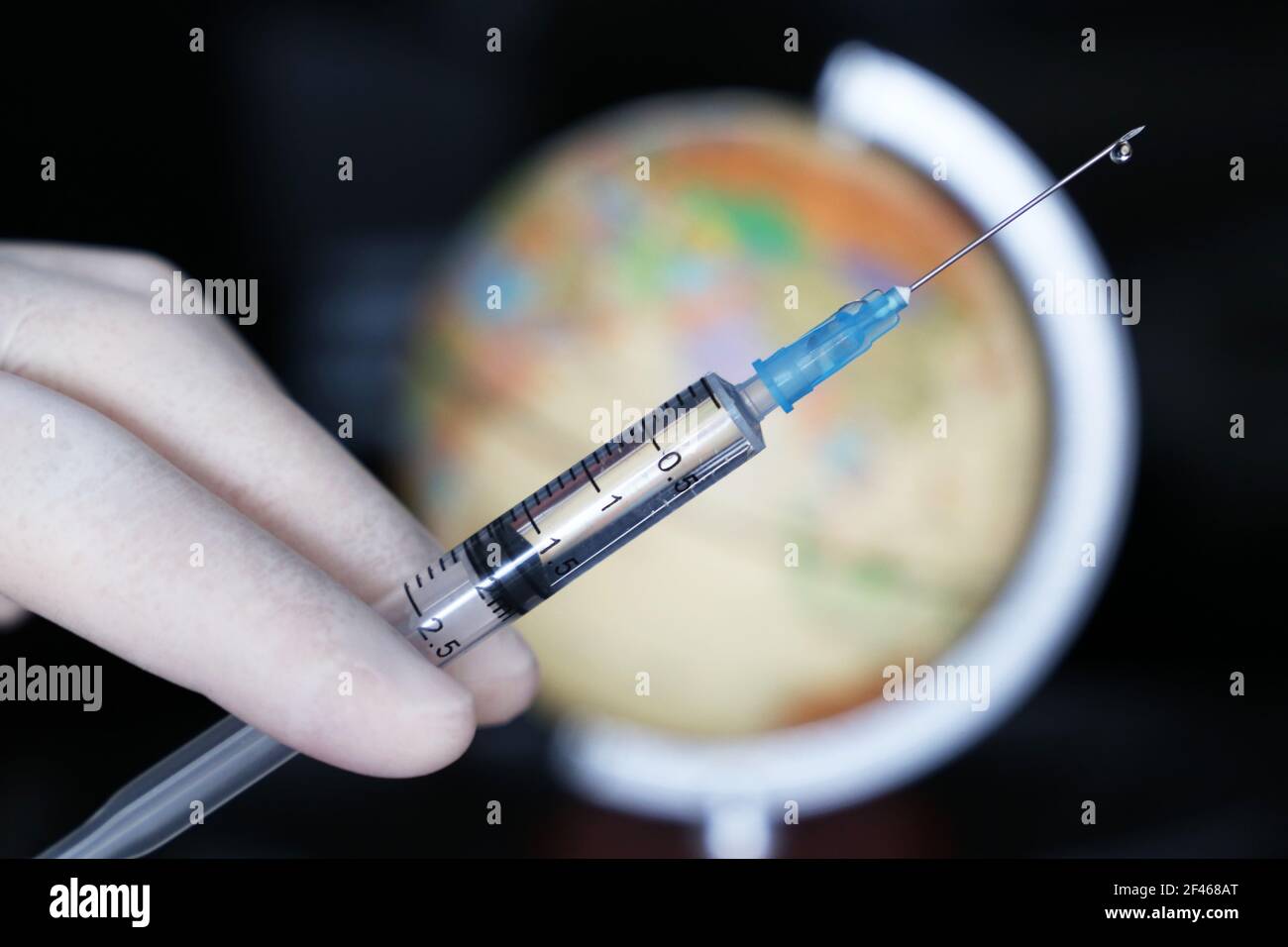 Vaccinazioni nel mondo, mano del medico con siringa sullo sfondo del globo. Concetto di assistenza sanitaria durante la pandemia di covid-19 Foto Stock