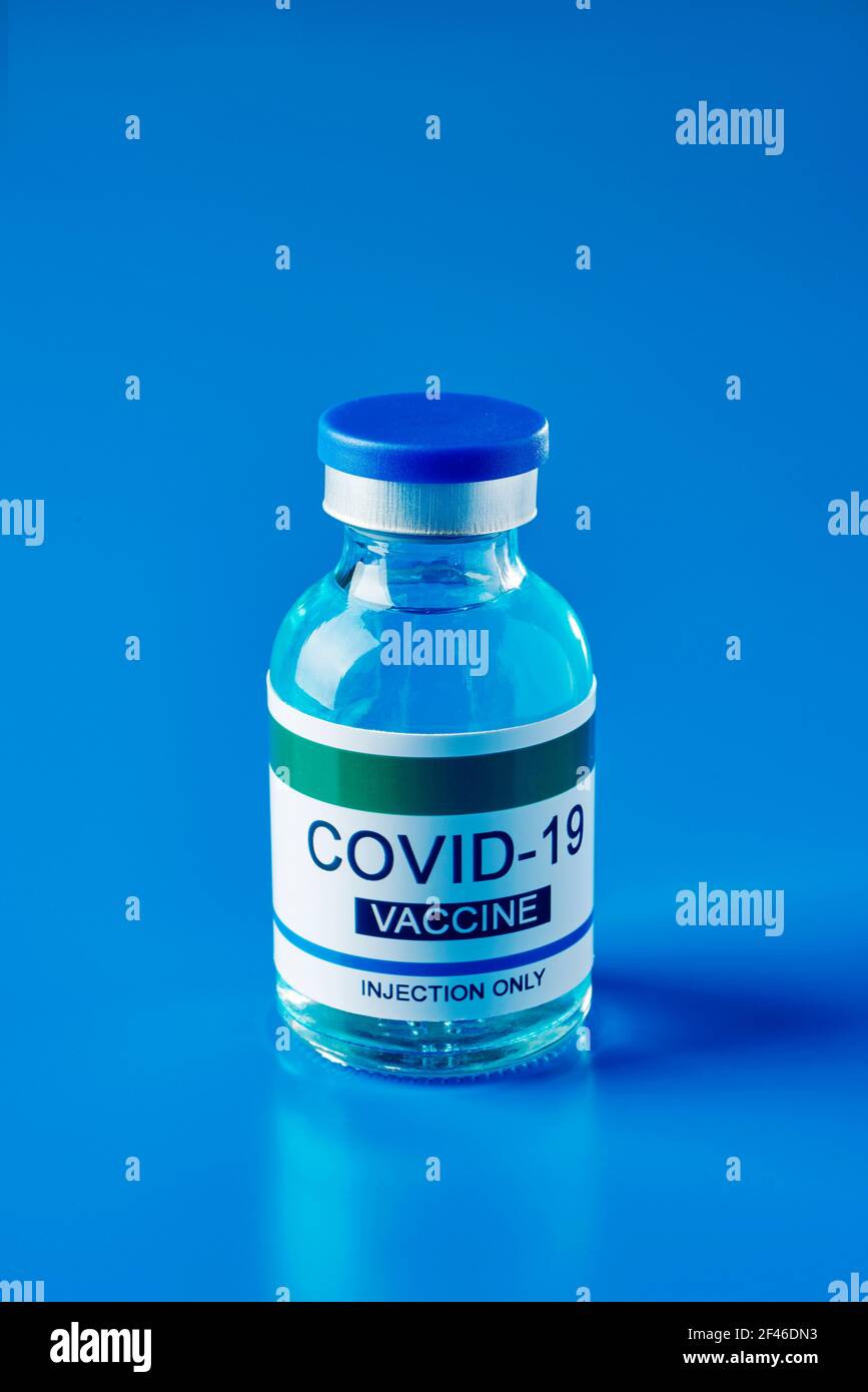 flaconcino simulato di un vaccino covid-19, con un'etichetta che riporta solo l'iniezione del vaccino covid-19, su sfondo blu Foto Stock