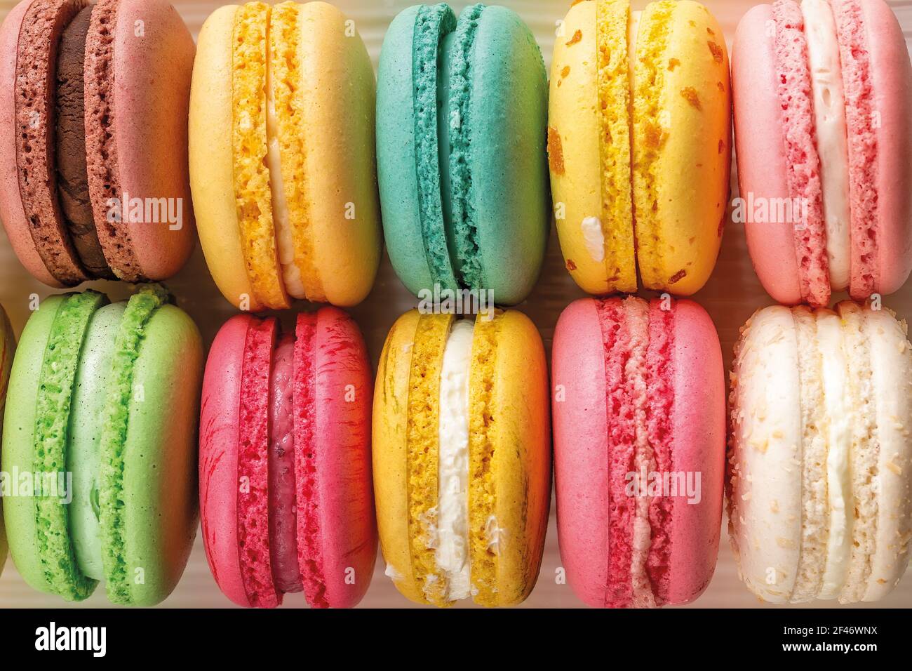 Primo piano di deliziosi macaroon multicolore come sfondo. Mockup del biglietto d'auguri con dolci torte di macaron multicolore. Meringa francese di mandorle. Foto Stock
