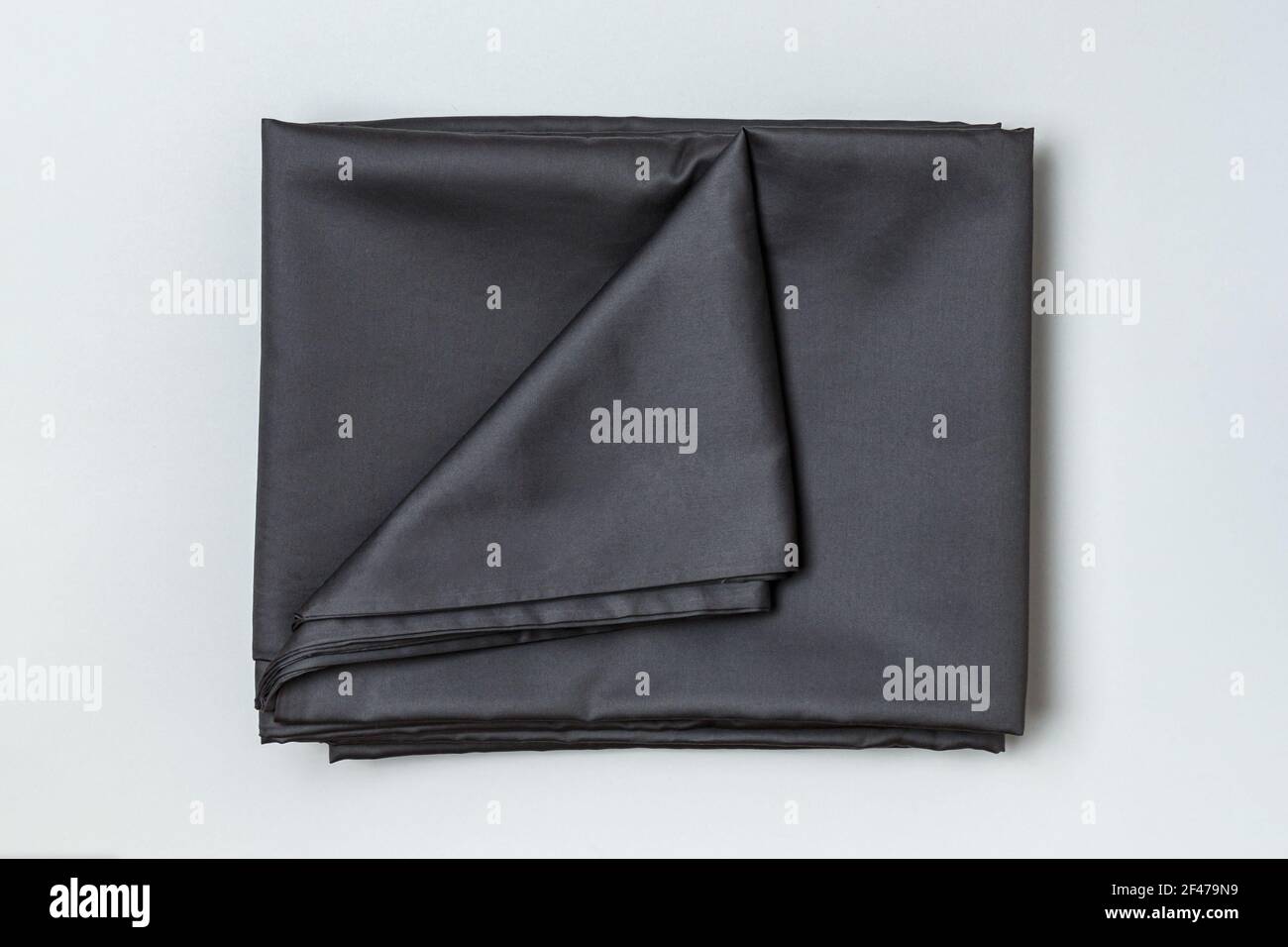 Vista ravvicinata di un set di lenzuola scure e copripiumino su sfondo grigio. Foto Stock