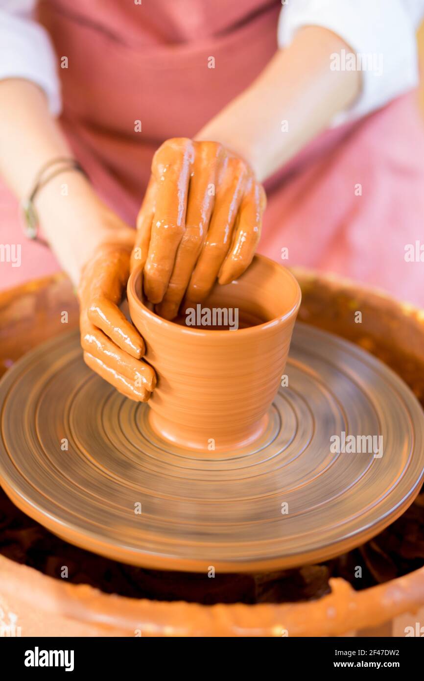 Le mani della donna scolpisce la tazza dal vaso di creta. Laboratorio di modellazione su ruota di vasaio. Foto Stock