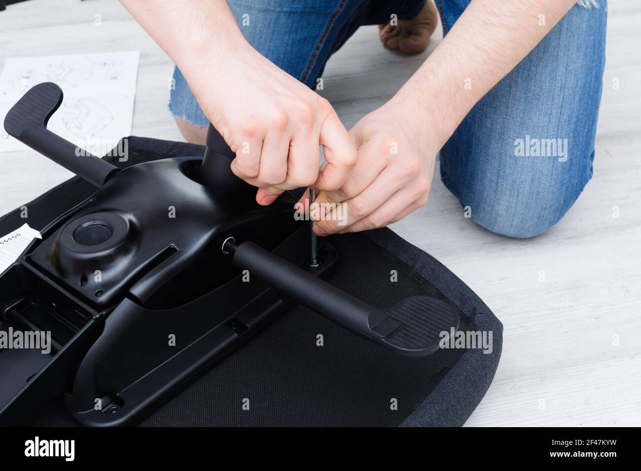 Meccanismo di sollevamento sedia a vite uomo caucasico. Montaggio della sedia da ufficio Foto Stock