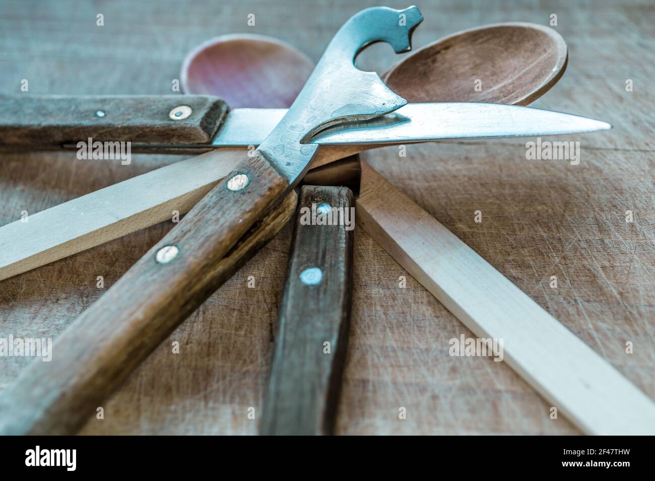 Un primo piano di coltelli e cucchiaio di legno su un tavolo Foto Stock