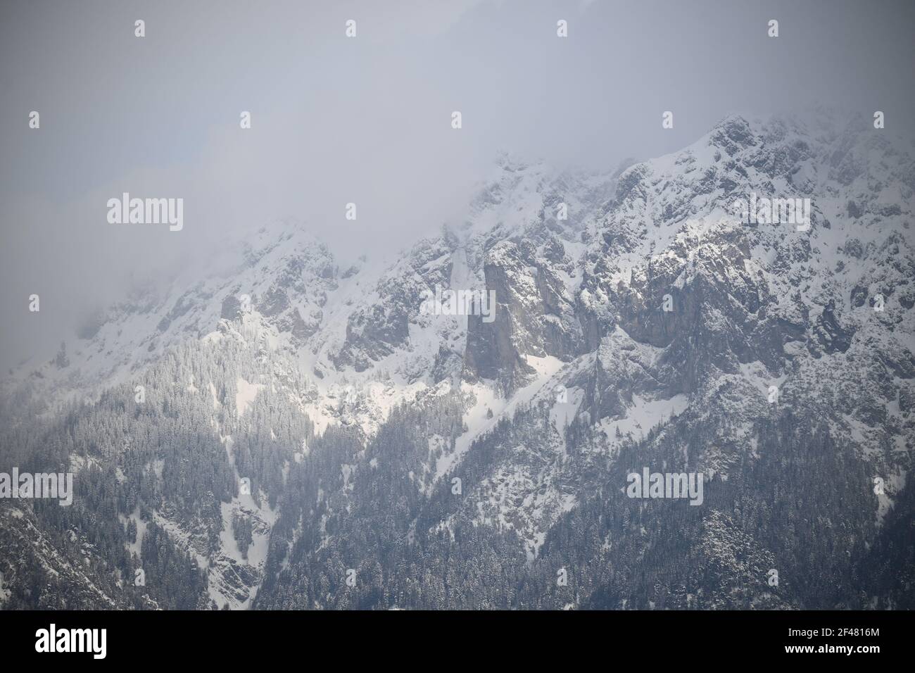 Raggi di sole che brillano su una montagna innevata attraverso alcune nuvole Foto Stock