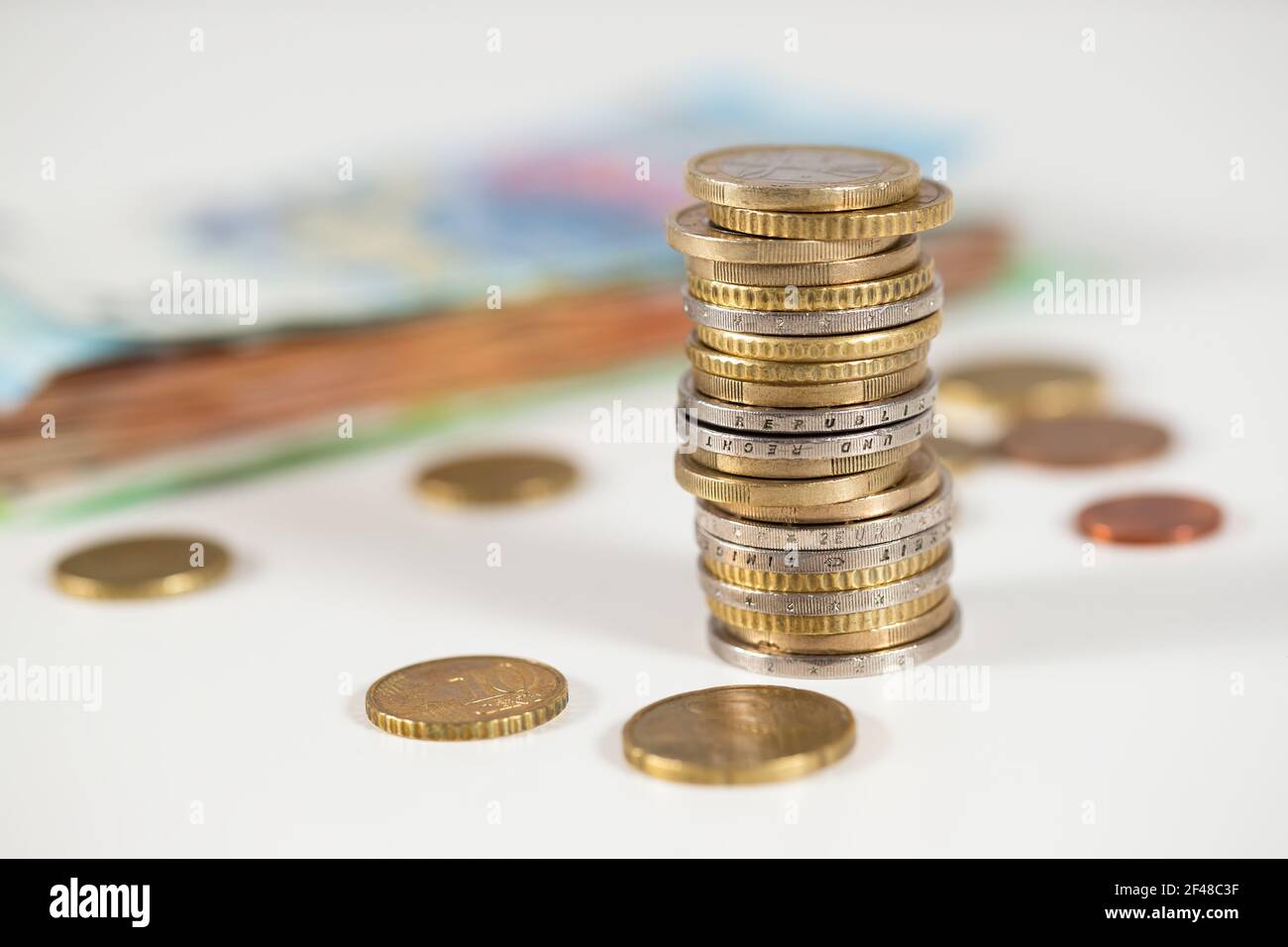 Monete in euro in colonna su tavola in ambiente bianco Foto Stock